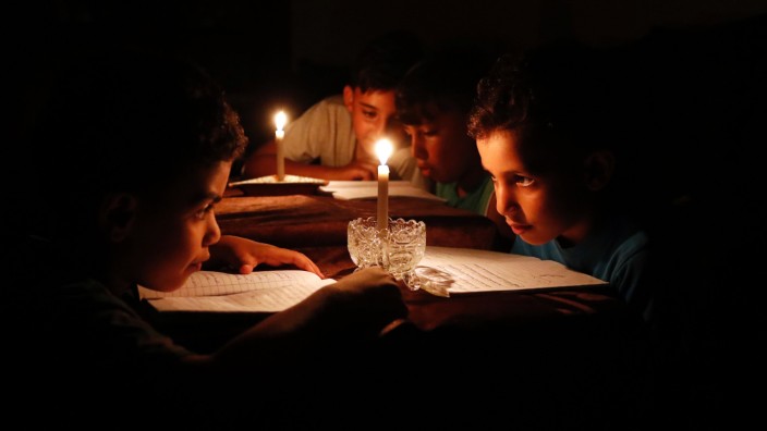 Gaza: Palästinensische Kinder lesen bei Kerzenschein, höchstens vier Stunden am Tag gibt es noch Strom in Gaza. Ein Ende ist erst einmal nicht absehbar: Israel will künftig 40 Prozent weniger Strom in den Gazastreifen liefern.
