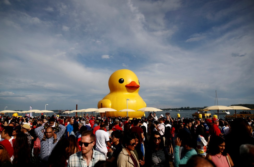People stand in front of a large inflatable duck installation during 'Canada 150' celebrations in Toronto
