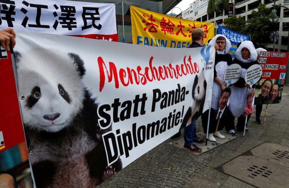 People protest before the arrival of German Chancellor Angela Merkel and Chinese President Xi Jinping outside the Zoo in Berlin