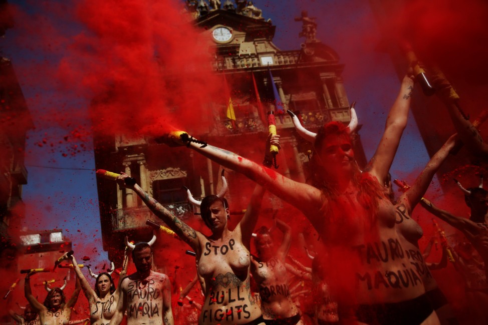 Animal rights protesters stand still after breaking mock banderillas containing red powder, which covered them during a demonstration for the abolition of bull runs and bullfights in Pamplona