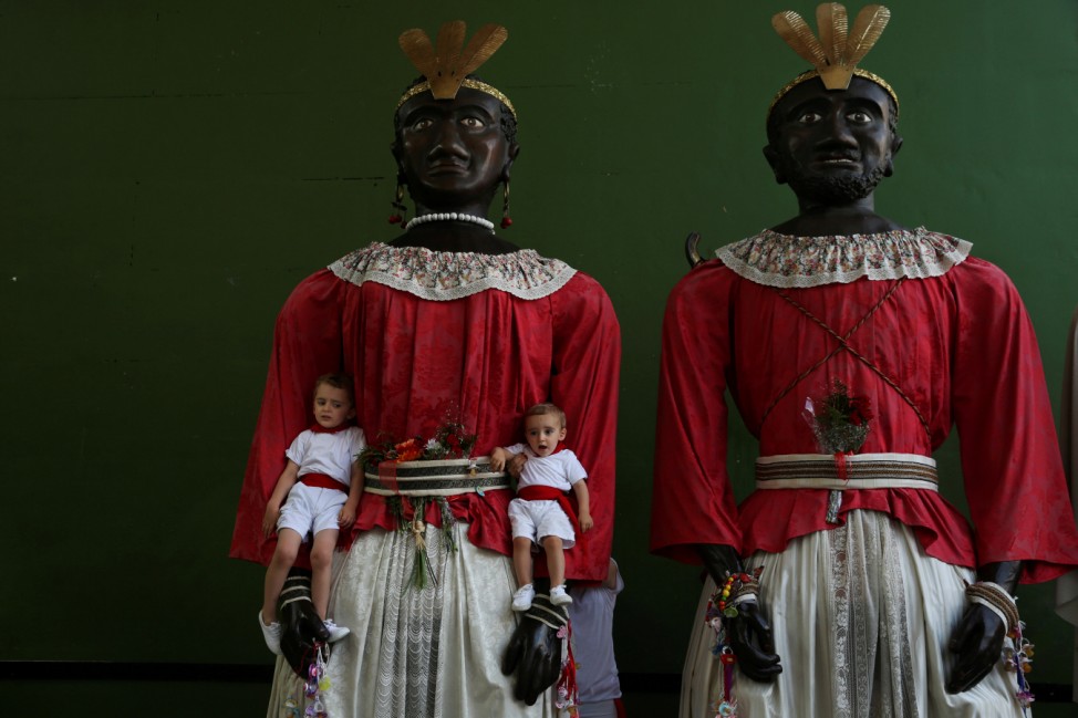 Children pose with two giants during San Fermin festival's 'Comparsa de gigantes y cabezudos' in Pamplona