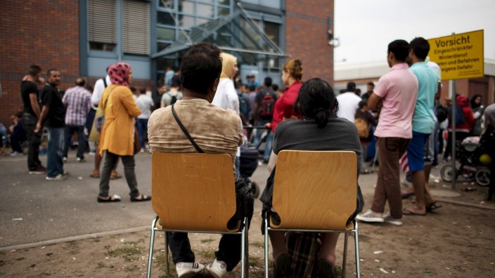 Asylum seekers wait in front of the Federal Office for Migration and Refugees (BAMF) at Berlin's Spandau district