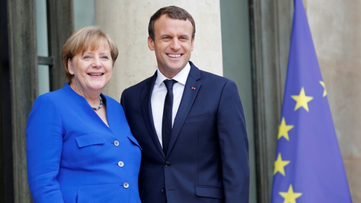 French President Emmanuel Macron arrives with German Chancellor Angela Merkel to attend a Franco-German joint cabinet meeting at the Elysee Palace in Paris