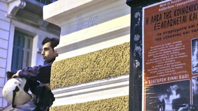 Zwischenfall in Griechenland: Ein Polizist steht in Athen neben einem Poster, das an den getöteten 15-jährigen Schüler erinnert.