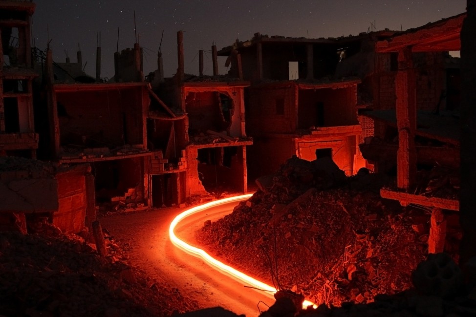 Damaged buildings are pictured at night in the rebel-held area, in the city of Deraa