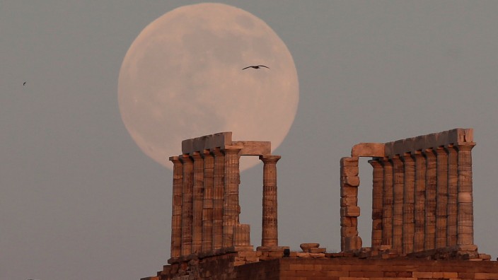 A fullmoon rises over the Temple of Poseidon, the ancient Greek god of the seas, in Cape Sounion, east of Athens