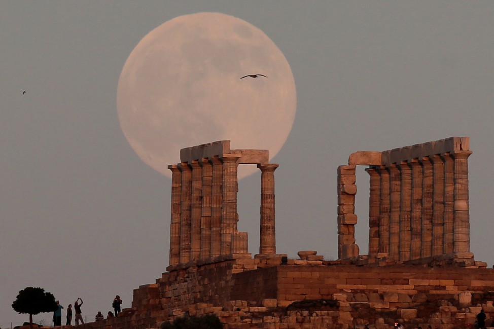 A fullmoon rises over the Temple of Poseidon, the ancient Greek god of the seas, in Cape Sounion, east of Athens
