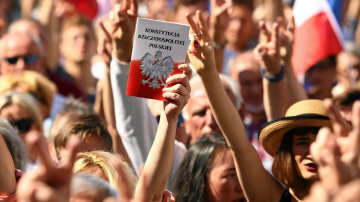 A protester holds a copy of the Polish Constitution during an opposition protest at the Market Square in Krakow