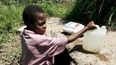Simbabwe: Ein kleiner Junge aus einem Vorort von Harare holt Wasser aus einem Kanal