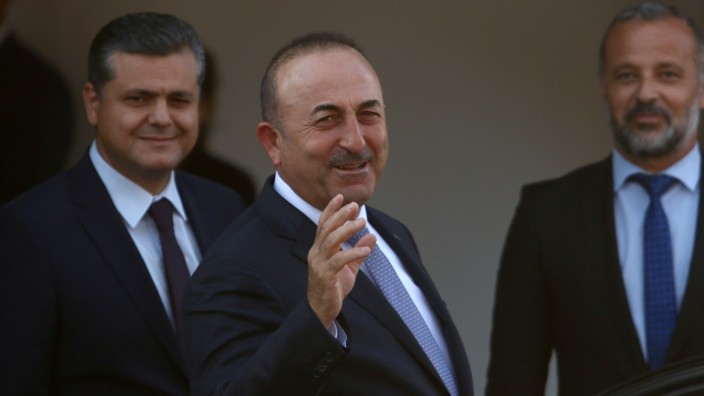 Turkey's Foreign Minister Mevlut Cavusoglu greets journalists during a visit in the Turkish Cypriot northern part of the divided city of Nicosia