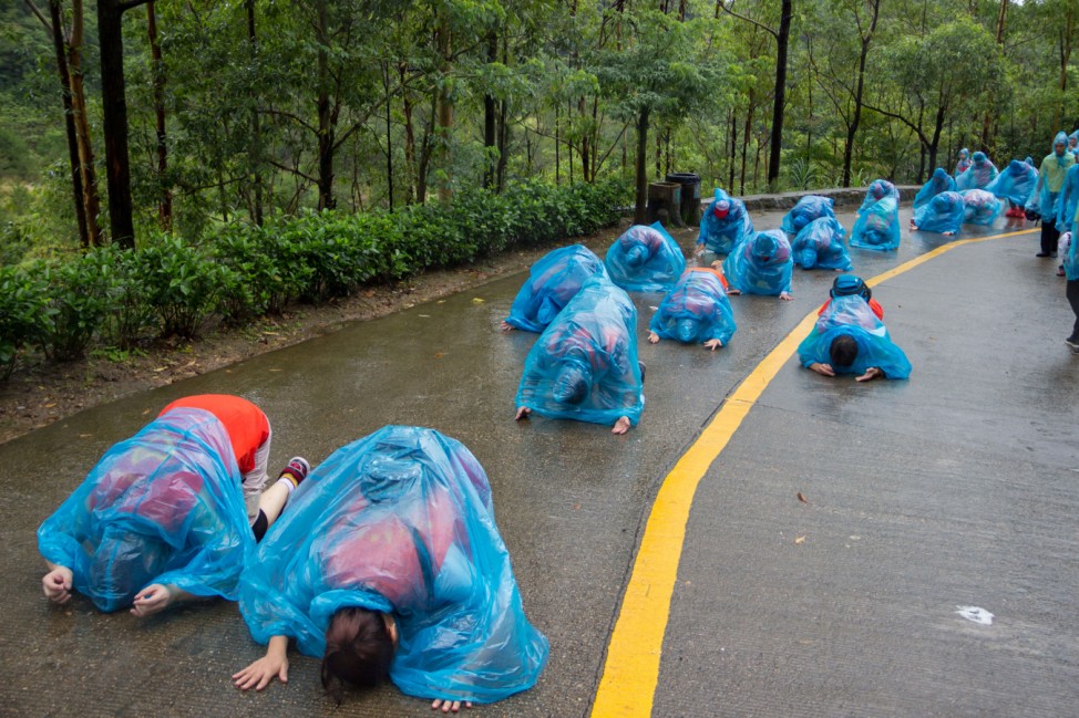 People kneel down as they pray at Guanyin mountain on a rainy day in Dongguan