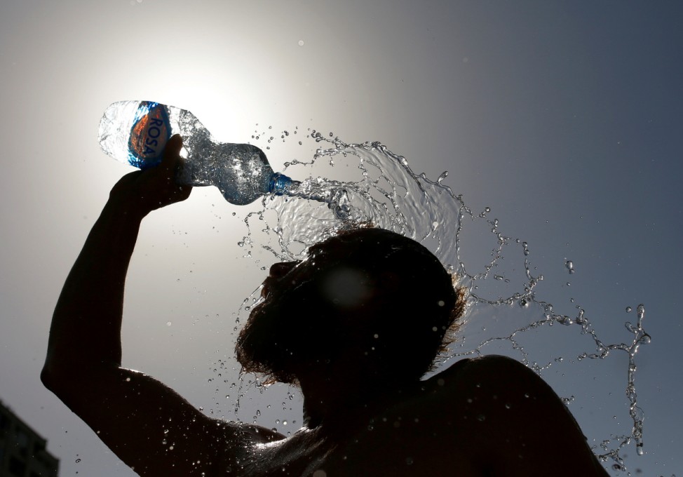 A man pours water on his face to cool off from hot weather in Skopje
