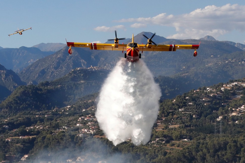 A Canadair firefighting aircraft drops water on a wildfire which burns a forest in Carros