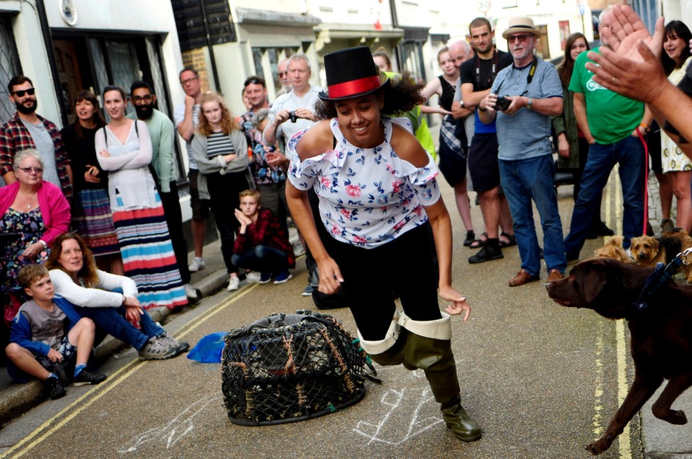 A participant is chased by a dog as she takes part in the traditional 'sea boot and top hat' race in Hastings