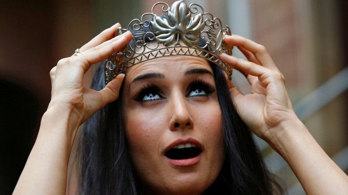 Syrian refugee Bahno holds a crown during the preparation for the crowning ceremony to the Trier wine queen in Trier