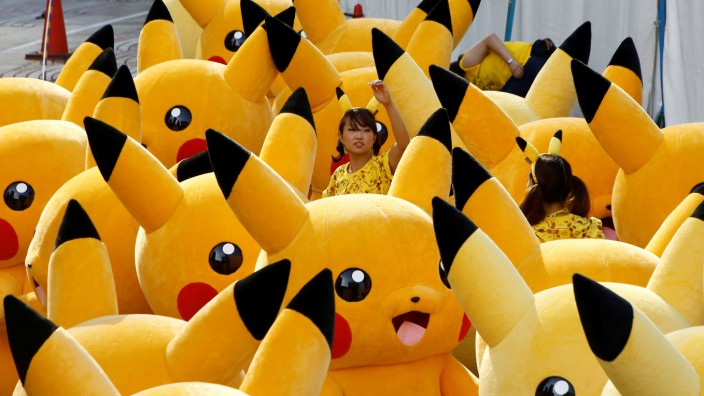 A staff guides performers wearing Pokemon's character Pikachu costumes as they prepare for a parade in Yokohama