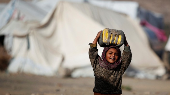 A girl carries a can to fill it up with water at a camp for internally displaced people in Dharawan, near the capital Sanaa