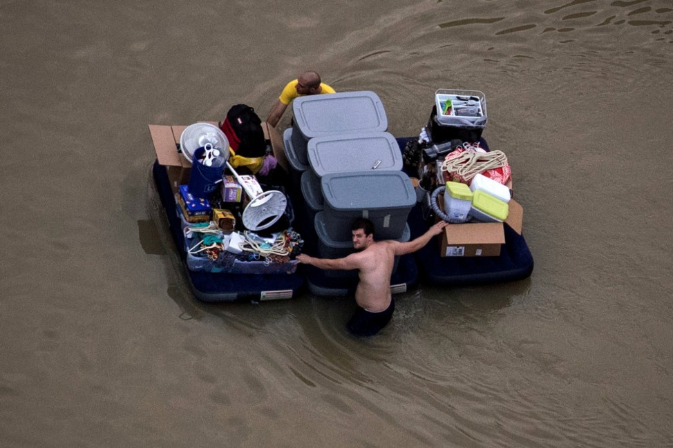 Residents wade with their belongings through flood waters brought by Tropical Storm Harvey in Northwest Houston