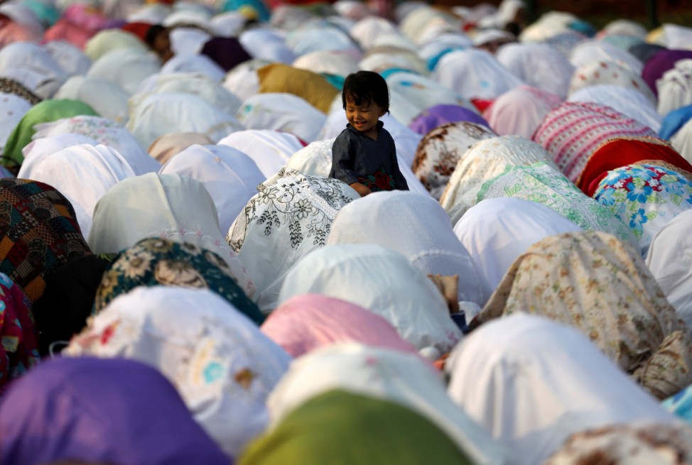 People attend prayers for the Muslim holiday of Eid al-Adha on a street outside of a mosque in Jakarta