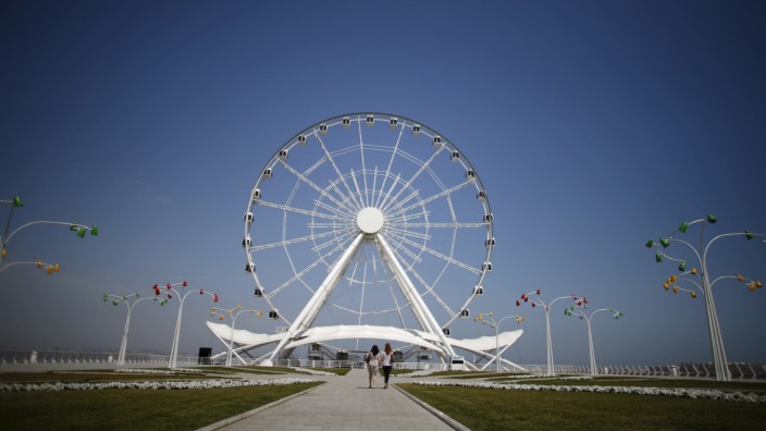Women walk towards the Baku Ferris Wheel, also known as the Baku Eye, in Baku