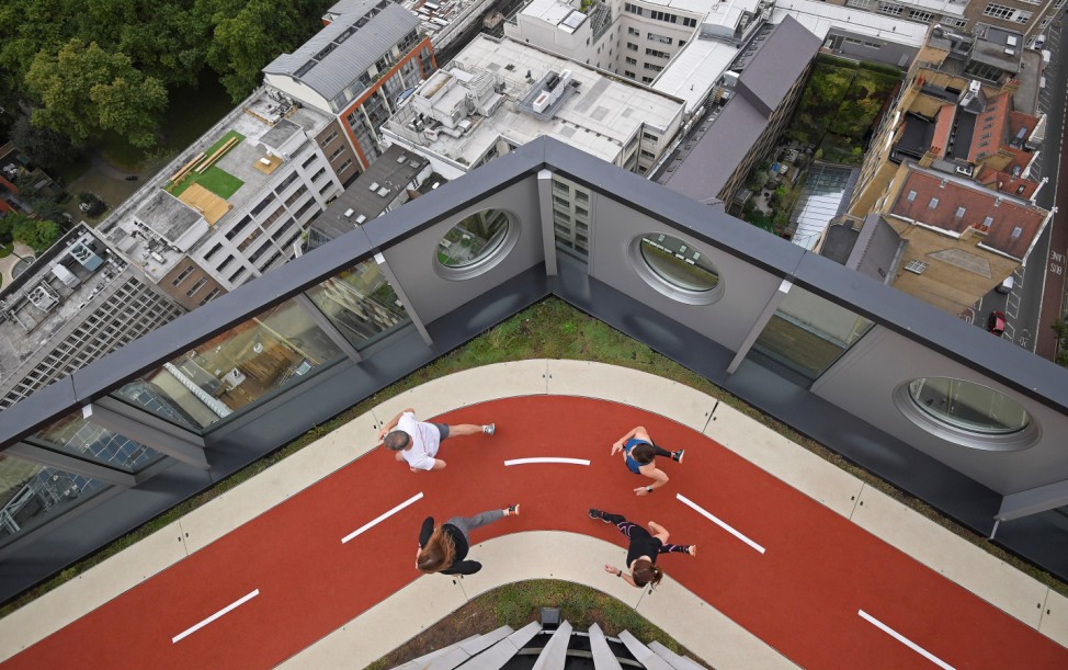 Workers pose as they run round a track, unveiled as the highest running track in London, at the White Collar Factory in the 'tech belt' hub near Old Street in London