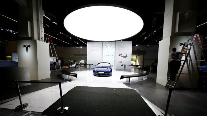 FILE PHOTO: People run preparations at the Tesla company booth during the media day at the Frankfurt Motor Show (IAA) in Frankfurt