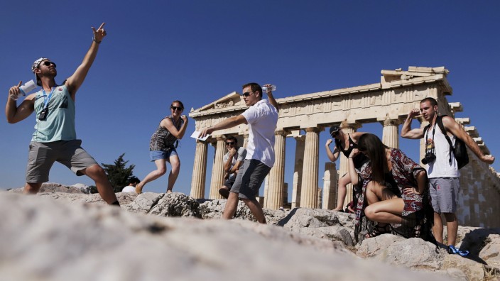 A group of tourists takes a selfie in front of the temple of the Parthenon atop the Acropolis in Athens; WIR