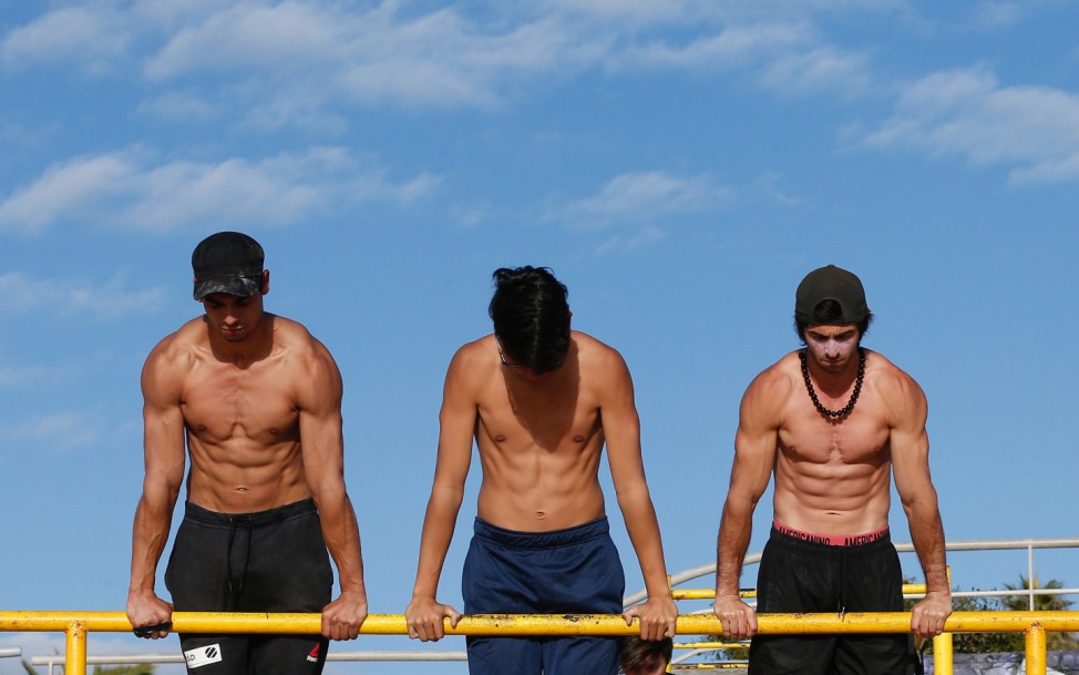 Men train during a session of gymnastics on a beach at Vina del Mar