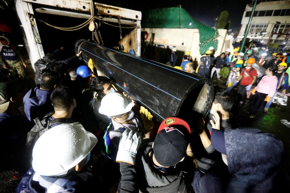 Workers carry a tube during the search for students at Enrique Rebsamen school after an earthquake in Mexico City