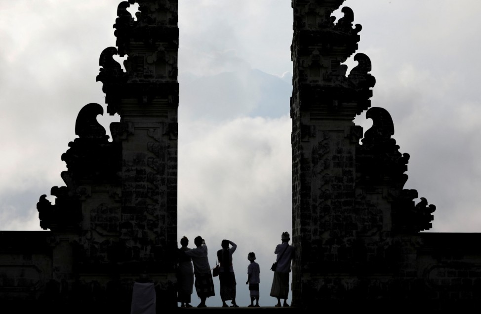 Balinese worshippers look at Mount Agung, enshrouded by clouds, from the gate of Penataran Agung Lempuyang temple, a day after the volcano's alert status was raised to the highest level, in Karangasem Regency, on the resort island of Bali