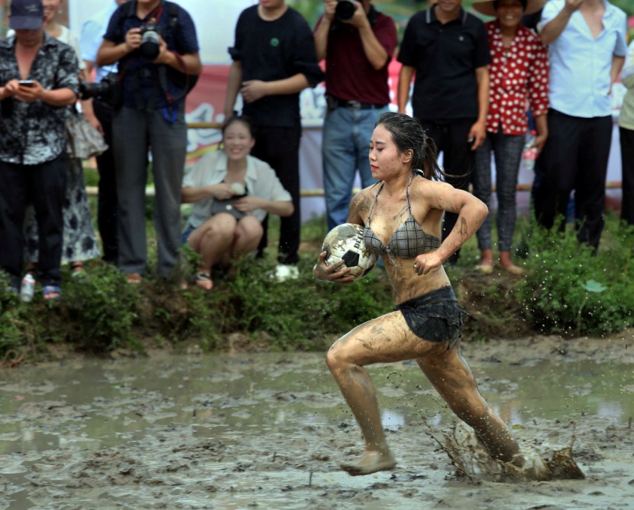 Woman runs with ball as she takes part in a mud football match in Jinhua