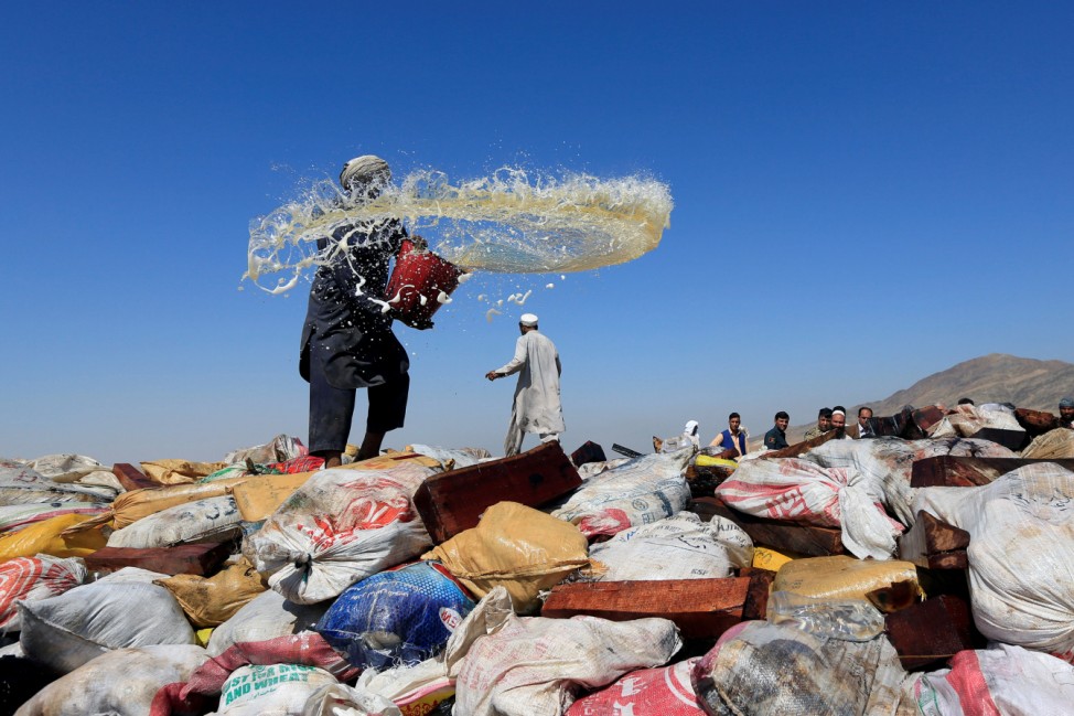 An Afghan man prepares to burn a pile of illegal narcotics on the outskirts of Jalalabad