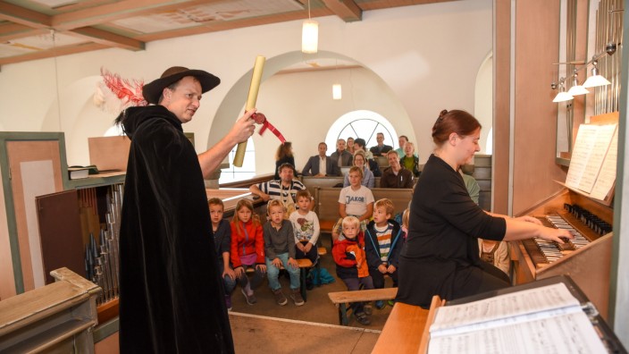 Andreas Pehl verkörpert alle Figuren : Andreas Pehl (links) schlüpft in verschiedene Rollen, Elisabeth Göbel spielt die Orgel und die Kinder hören gebannt zu.