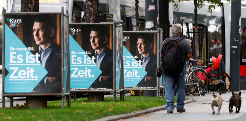 A man walks his dogs past election campaign posters of People's Party in Vienna