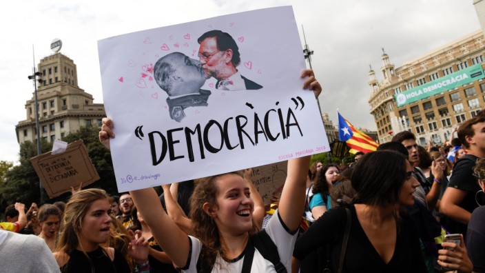 A woman holds up a banner reading 'Democracy' depicting former Spanish dictator Francisco Franco kissing Spanish Prime Miniser Mariano Rajoy during a protest one day after the banned independence referendum in Barcelona