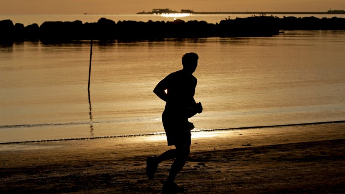A man runs at sunrise along the beach in Rimini