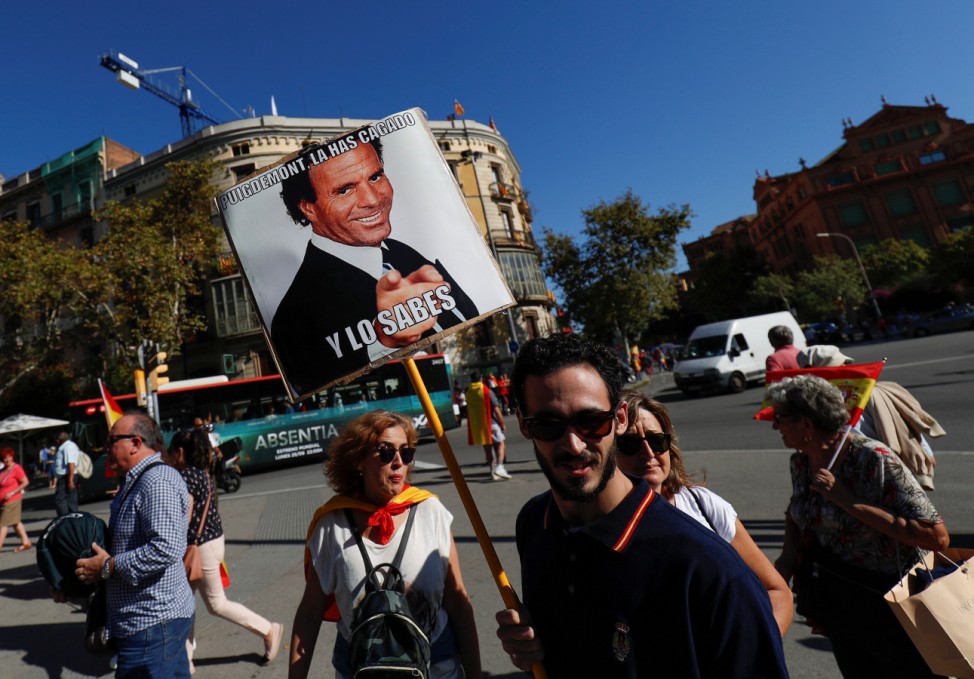 A man carries a sign depicting Spanish singer Julio Iglesias which reads 'Puigdemont you messed up and you know it'  as demonstrators gathered for a pro-union demonstration organised by the Catalan Civil Society organisation in Barcelona