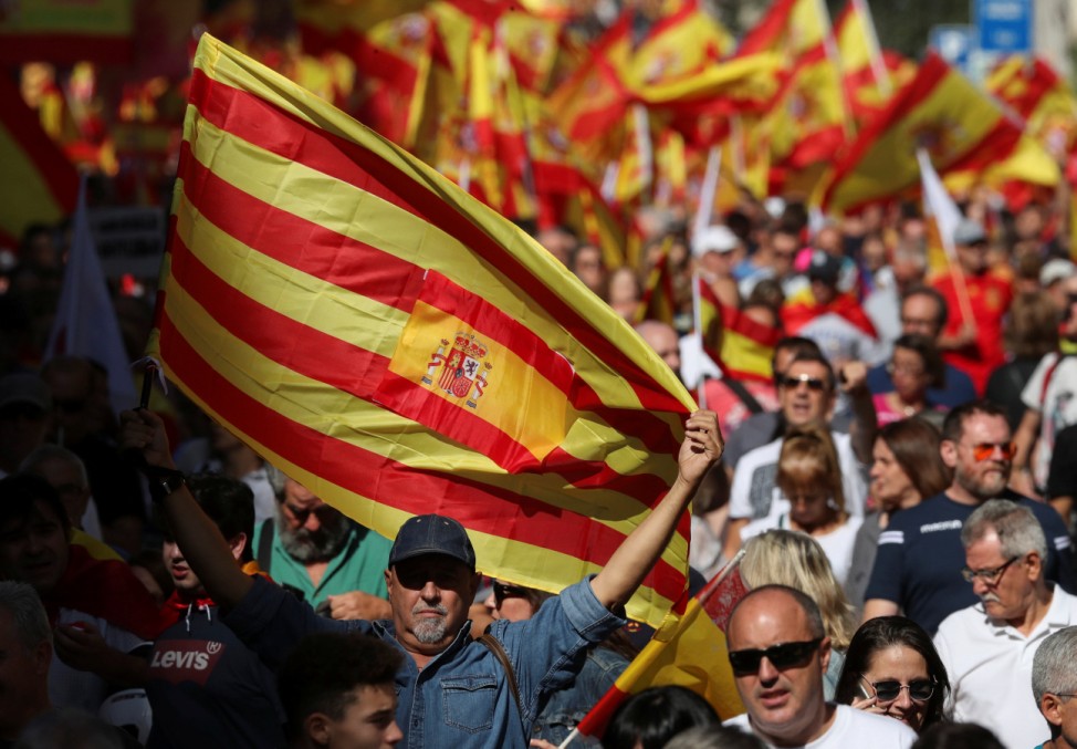 People wave Spanish and Catalan flags as they attend a pro-union demonstration organised by the Catalan Civil Society organisation in Barcelona