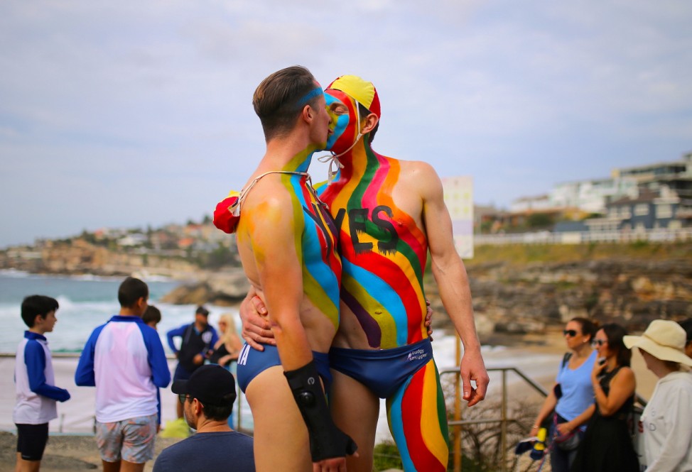 Two men kiss as they participate in an event supporting a 'Yes' vote in a non-binding poll at Sydney's Tamarama Beach