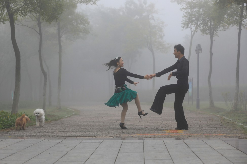 People dance in a park on a foggy day in Huai'an