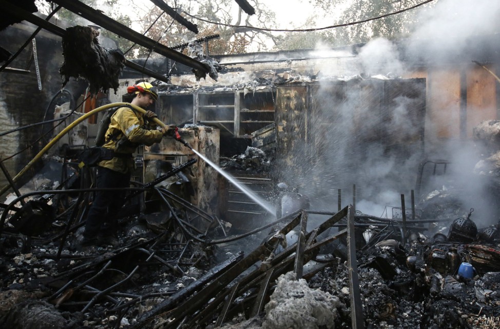 Ein Feuerwehrmann löscht Glutnester in einem ausgebrannten Haus in Kalifornien.
