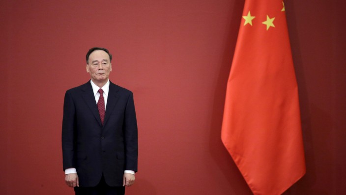 FILE PHOTO: China's Politburo Standing Committee member Wang Qishan stands next to a Chinese flag in Beijing