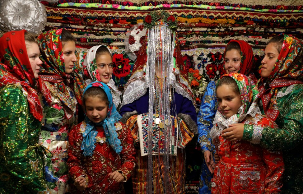 Bulgarian Muslim bride Lilova poses in front of the dowry wearing a special make-up called 'ghelina' during her wedding ceremony in the village of Draginovo
