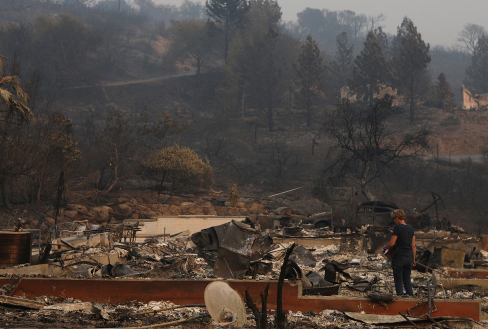 A woman surveys the remains of a home destroyed by wildfire in Napa