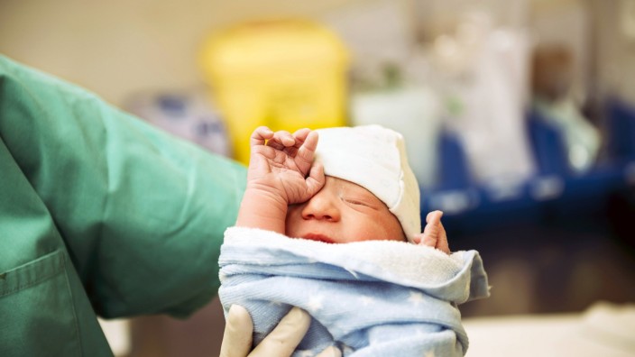 Newborn girl wrapped in a towel holded by the doctor in the delivery room model released Symbolfoto