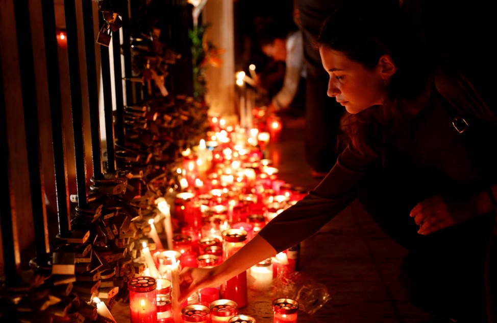 A woman places a candle on the Love monument during a silent candlelight vigil to protest against the assassination of investigative journalist Daphne Caruana Galizia in a car bomb attack, in St Julian's