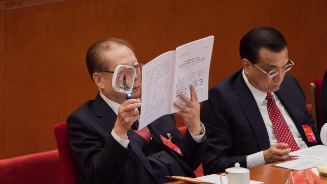 On the death of Jiang Zemin: On the podium, Xi Jinping explains his theory of the "Socialism for a new era".  Jiang Zemin reads it - with a fairly large magnifying glass.