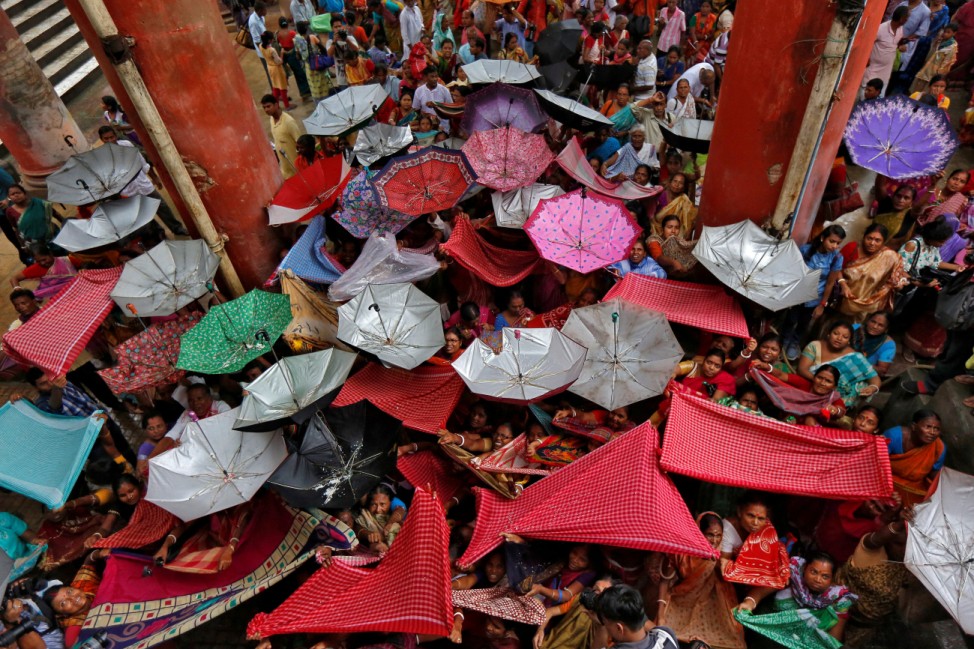 Hindu devotees hold up clothes and umbrellas to receive rice as offerings being distributed by a temple authority on the occasion of the Annakut festival in Kolkata