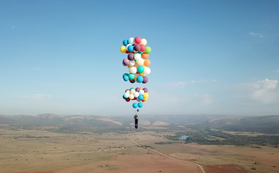 Tom Morgan, from Bristol-based company The Adventurists, flies in a chair with large party balloons tied to it near Johannesburg, South Africa