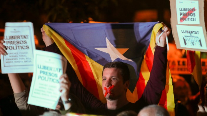 A man with his tapped mouth holds an Estelada (Catalan separtist flag) during a gathering in support of the members of the dismissed Catalan cabinet after a Spanish judge ordered the former Catalan leaders to be remanded in custody pending an inve